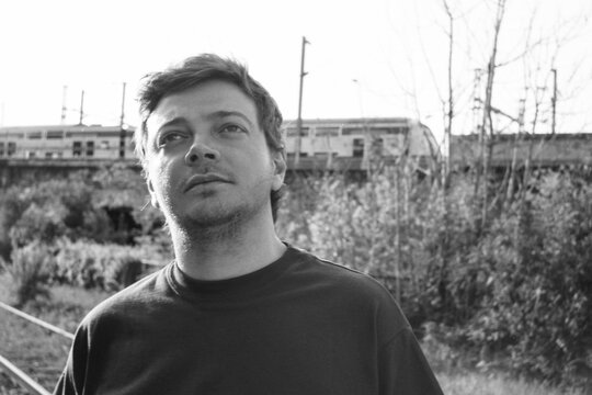 Man Looks Contemplatively as Train Passes in Black and White