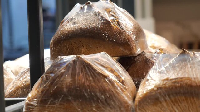 Freshly baked loaves of artisan bread wrapped in plastic film on display at bakery