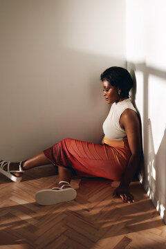 Woman sit on floor in sunlight in colorful dress
