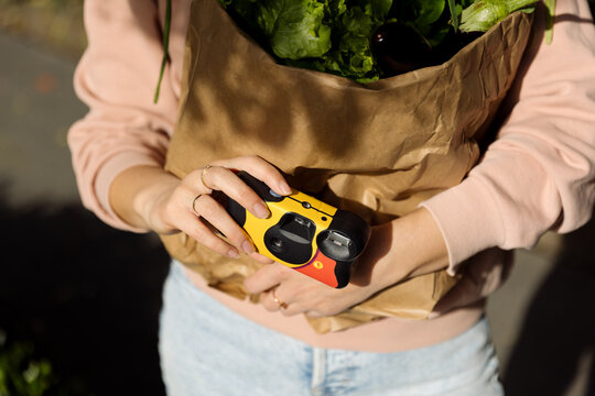 A young woman holds a disposable film camera in her hands.