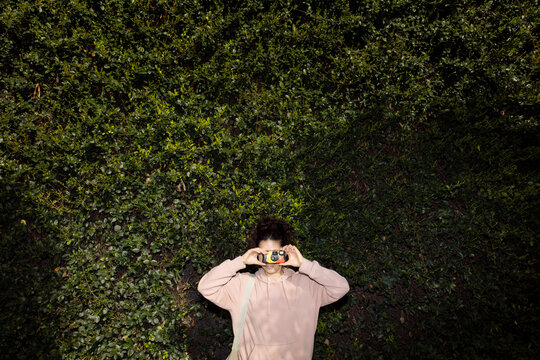 A young woman takes a picture with a disposable film camera