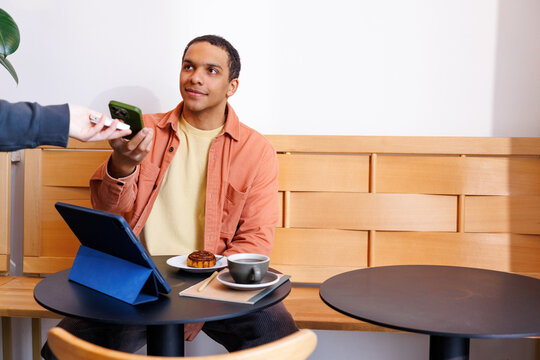 Man Making Mobile Payment Paying with Phone in Caf&eacute;