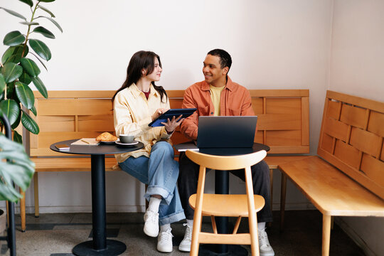 Coworkers Smiling Over Tablet and Laptop