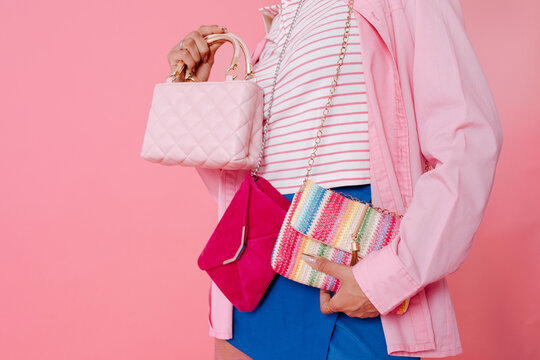 Anonyous woman holding pink, fuchsia and rainbow handbags