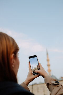 A woman takes pictures of a mosque