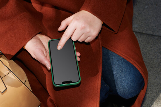 Individual interacts with smartphone while seated outdoors in autumn