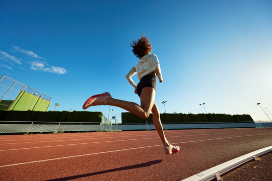 Runner in motion on a track under bright blue sky