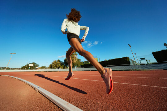 Runner training on an outdoor track during a sunny afternoon