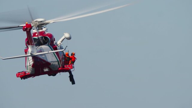 MADRID, SPAIN - OCTOBER 12, 2025: Video footage of a coast guard helicopter performing a winch rescue. A rescue swimmer in a drysuit is lowered or raised as the chopper hovers, then it flies away