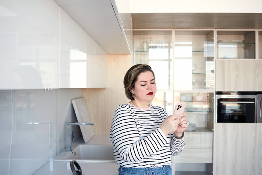 Woman using smartphone at the kitchen