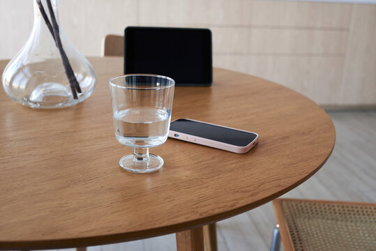 Modern room with glass of water and smartphone on wooden table