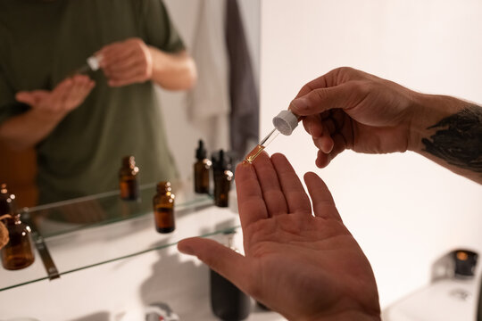 Man taking drop of facial serum on finger