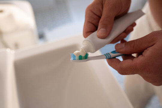 Man squeezing toothpaste on toothbrush