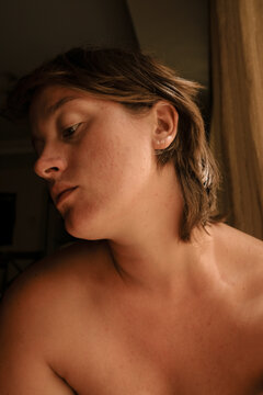Woman reflecting in soft light while sitting near a window 
