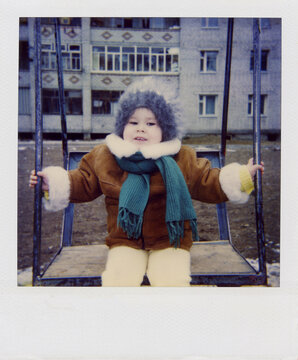 Smiling Child on Swing in Winter Coat
