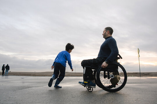 Man in Wheelchair with Child Outdoors at Scenic Dusk