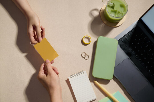 Hands exchanging a gold card on a workspace, with a matcha latte