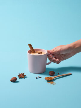 Hand Holding A Cup of Spiced Chai Latte with Aromatic Ingredients