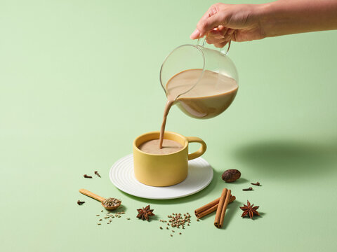 Warm Spiced Milk Being Poured Into a Mug With Cinnamon Sticks