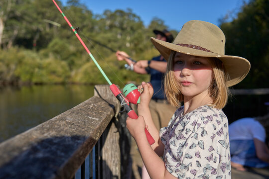 Young Girl Fishing on Wooden Railing in Rural Countryside Setting