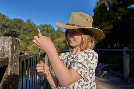 Young Girl Fishing on a Wooden Dock in a Countryside Setting