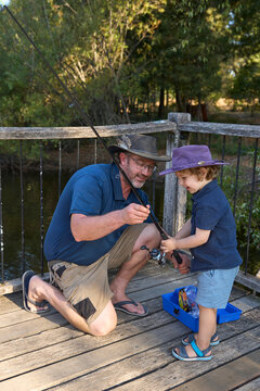 Dad teaching young son how to set fishing rod