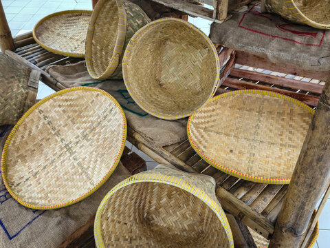 Handcrafted artisanal bamboo winnowing trays and woven harvest baskets on rustic burlap display, typical of rural Indonesia. Tampah and Bakul in Indonesian