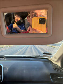 POV Father and Son Reflected in Car Visor Mirror on Open Road
