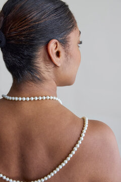 Woman wearing a pearl necklace on her back