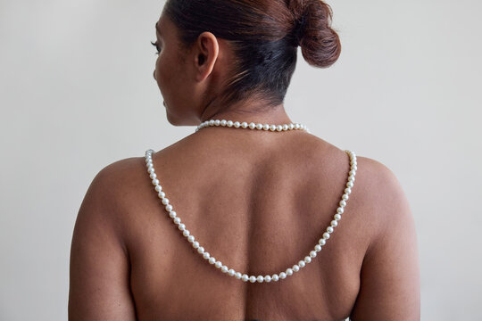 Woman wearing a pearl necklace on her back