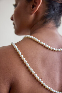 Woman wearing a pearl necklace on her back
