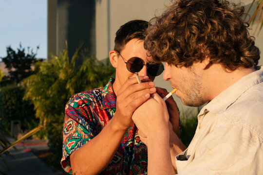 Two friends lighting cigarettes outside a hotel