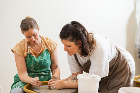 Two women focused on shaping clay in pottery class