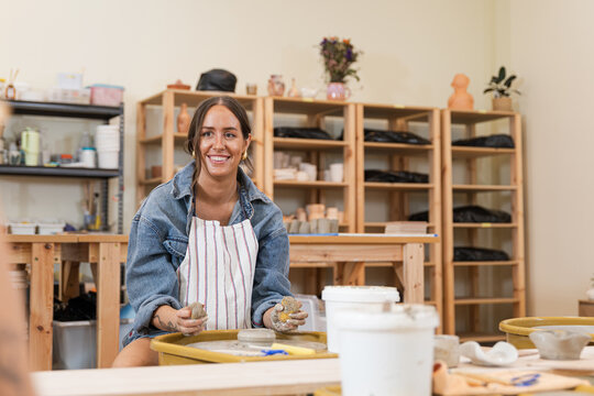 Woman smiling while shaping clay on potter's wheel
