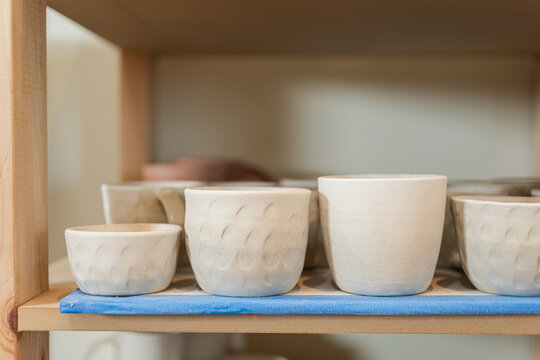 Cups in various sizes placed on wooden shelf