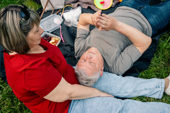 Person resting with head on lap during picnic on grass