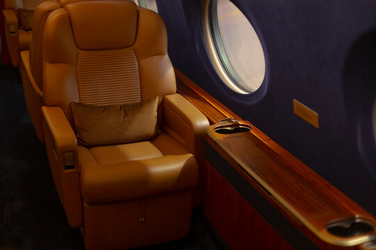 Opulent aircraft interior. Exclusive leather cabin features. Luxurious Gulfstream seat with lighting and comfort. Elegant window side seat in private jet with plush furnishings