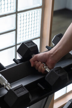Close-up of a hand grasping a 4kg dumbbell, ready for weightlifting