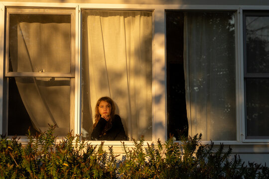 Girl Looking out the window at sunset