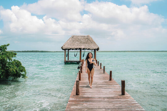 Latina woman with little dog on pier by tropical lagoon in Mexico
