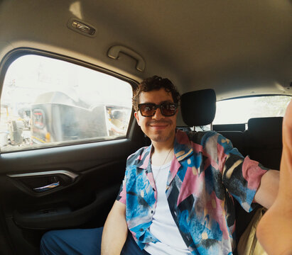 Tourist taking a selfie in the backseat of Mumbai taxi