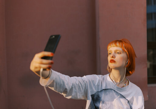 Portrait of a Person Taking a Selfie Outdoors Against a Pink Wall