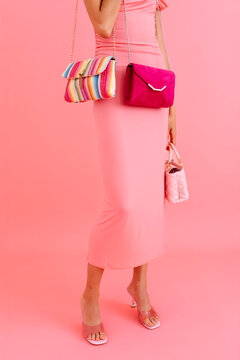 Unrecognizable woman showing colorful handbags and pink dress