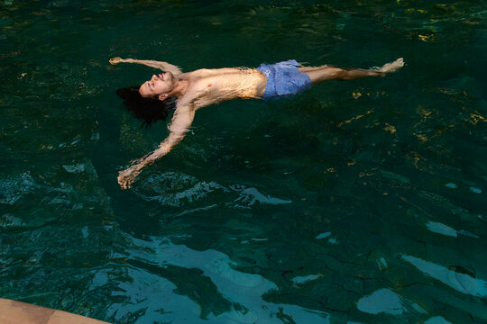 Man Relaxing and Floating in clear pool water in Siem Reap, Cambodia