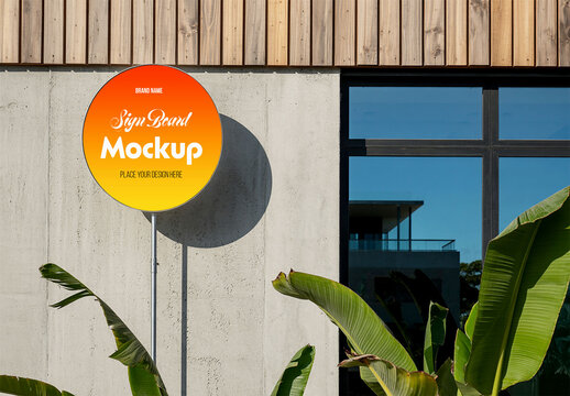 Circular Outdoor Sign Board Mockup on Concrete Wall with Tropical Foliage