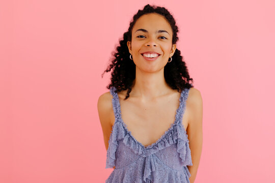 Young woman smiling with frilly top and pink background