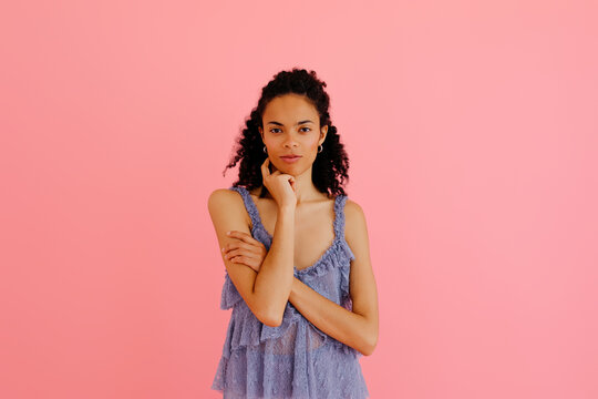 Young pensive woman posing with crossed arms and hand on chin