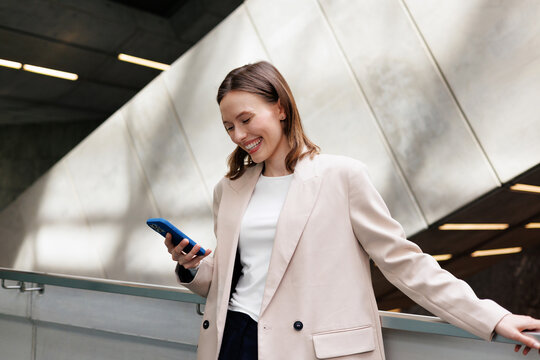 Cheerful Elegant Business woman Using Smartphone in modern workspace 
