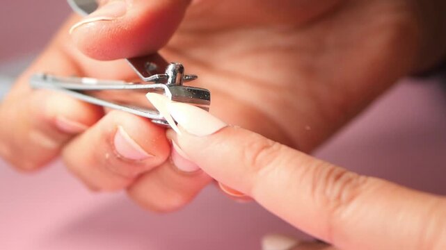 Close up of hands using nail clippers to trim fingernails