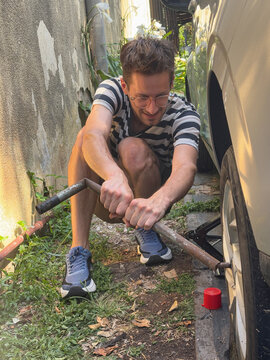 Young Man Changing a Car Tire UGC